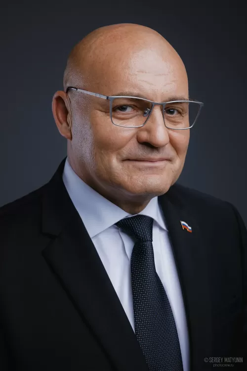 Деловой портрет лысого мужчины в очках и классическом костюме с государственным значком на лацкане для бизнес съемки