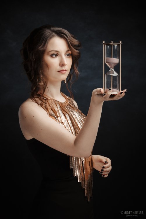 Студийный портрет девушки в золотом платье с песочными часами для профессиональной рекламной съемки