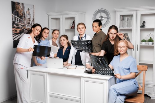 Команда врачей проводит профессиональный медицинский консилиум и изучает рентгеновские снимки в светлом кабинете клиники