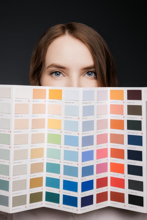 Девушка выбирает оттенки из палитры красок для интерьерной студийной съемки или ремонта квартиры