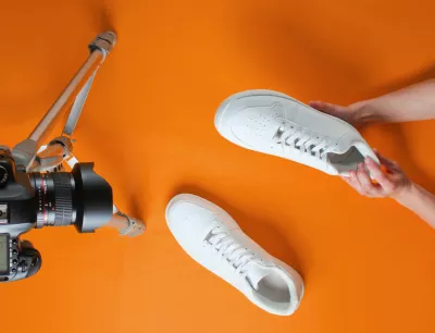 Women reviews new white sneakers with camera on tripod on orange background. Top view. Minimalism